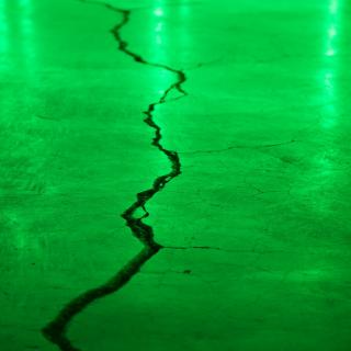 Crack in a concrete floor, illuminated by green light. 
